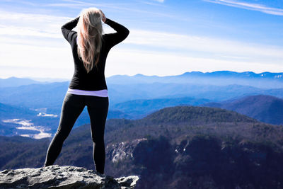 Rear view of man standing on mountain against sky