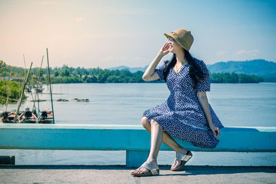 Full length of woman sitting against sea