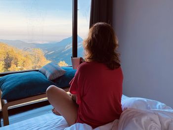 Rear view of woman sitting on bed