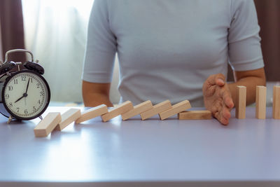 Midsection of woman blocking toy blocks while sitting at table