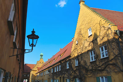 Low angle view of street light by building against sky