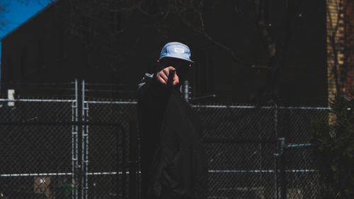Rear view of man photographing through chainlink fence