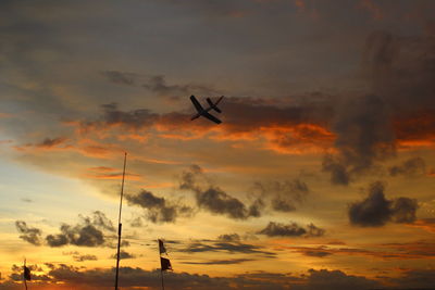 Low angle view of silhouette airplane against sky during sunset