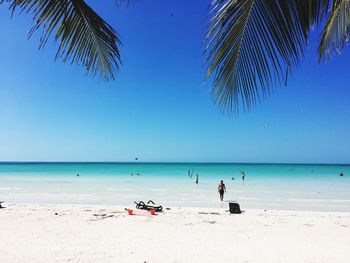 People on beach against clear blue sky