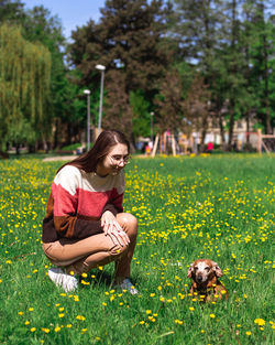 Charming young lady dressed in coloful sweater playing with her daschund dog. animal love concept