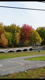 Park by river in city against sky