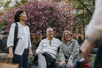 Happy male and female senior friends talking to each other at park