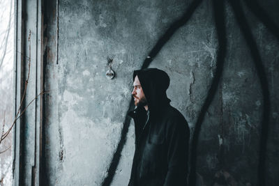 Young man smoking cigarette against wall