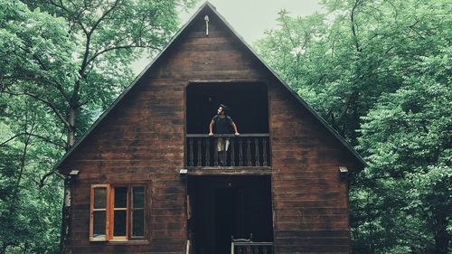 Man looking out the balcony of a forest house