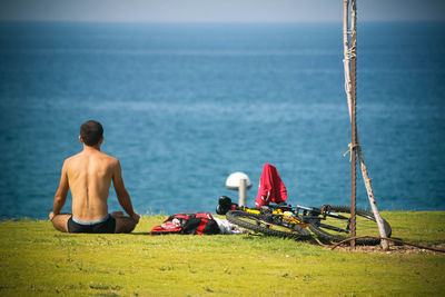 Shirtless man overlooking calm sea