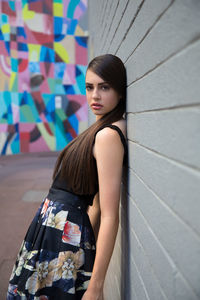 Portrait of teenage girl wearing dress leaning on wall 