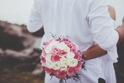 Midsection of man holding flower bouquet