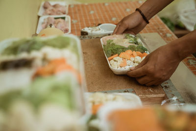 Cropped hand of man holding food in container