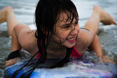 Close-up of smiling girl on surfboard