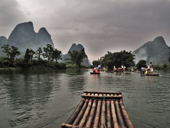 Wooden rafts in river against cloudy sky