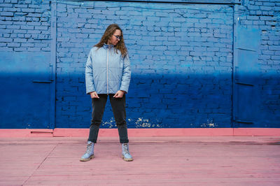 Full length of woman standing against wall