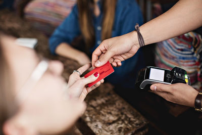 Close-up of female customer giving credit card to owner at restaurant