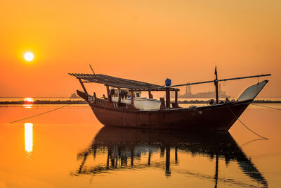 Fishing boat in sea against sky during sunset