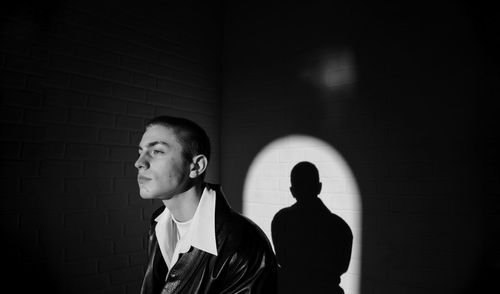 Portrait of a young man standing against wall