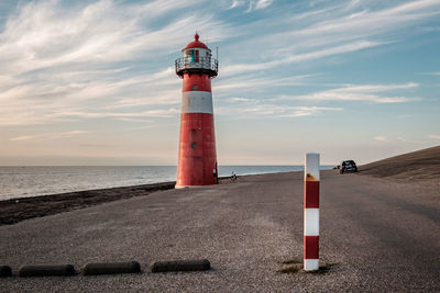 Lighthouse by sea against sky