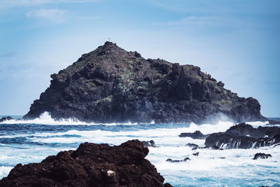 Rock formation on sea shore against sky