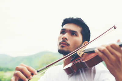 Man playing violin on field against clear sky