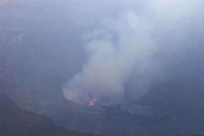 Smoke emitting from volcanic mountain against sky