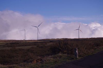 Wind turbines on field against sky