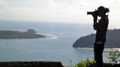 Man photographing sea against sky