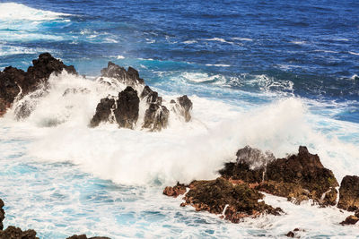 Panoramic view of waves breaking on rocks at shore