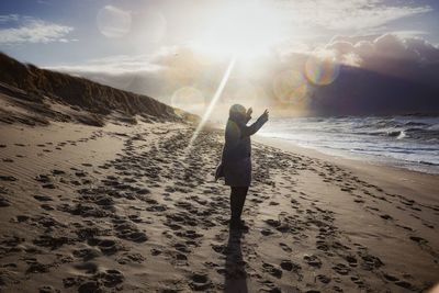 Man standing at beach against sky during sunset