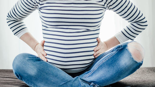 Midsection of woman sitting on sofa