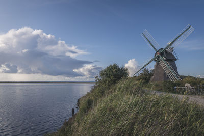 Traditional windmill on land against sky