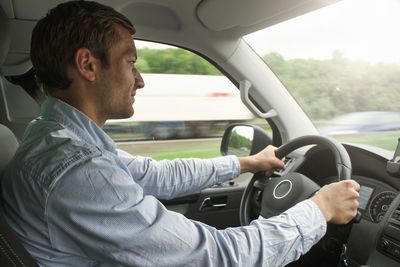 Side view of man driving car