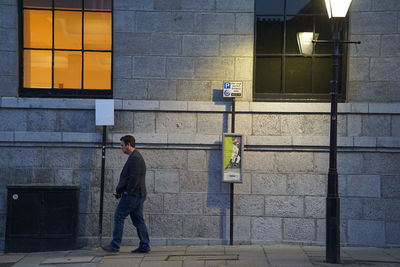 Full length rear view of man walking on street against building