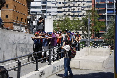 Woman photographing crowd on sidewalk in city