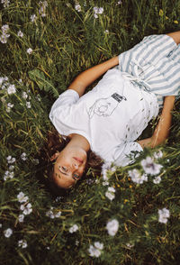 Directly above portrait of young woman lying down on grass