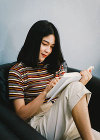 Young woman looking away while sitting on mobile phone