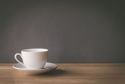 Coffee cup on table against wall