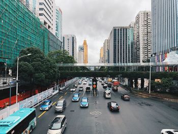 Traffic on city street by buildings against sky