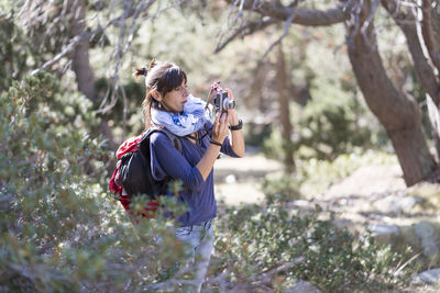 Woman photographing by plants outdoors