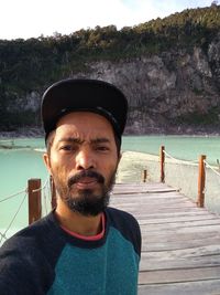 Portrait of young man standing by lake