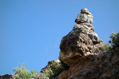 Low angle view of rock against clear blue sky