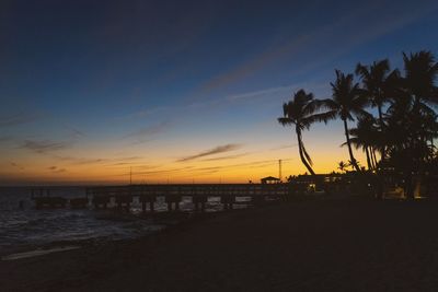 Silhouette palm trees on beach against sky during sunset