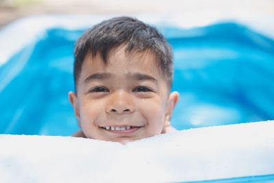 Close-up portrait of smiling boy swimming in pool