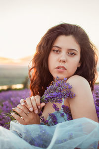 A beautiful young girl against the sunset and a beautiful sky in a lavender field. 