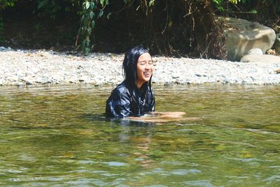 Portrait of smiling young woman swimming in water