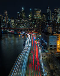 High angle view of light trails on road against buildings in city at night