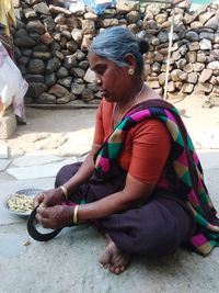 Full length of woman sitting on pebbles