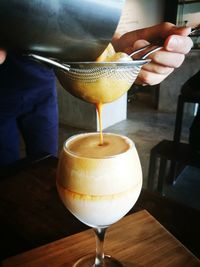 Midsection of man pouring juice in glass through strainer